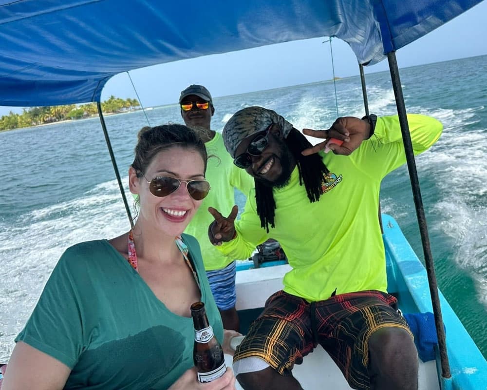 A group of three people smile and enjoy a boat ride on the water.